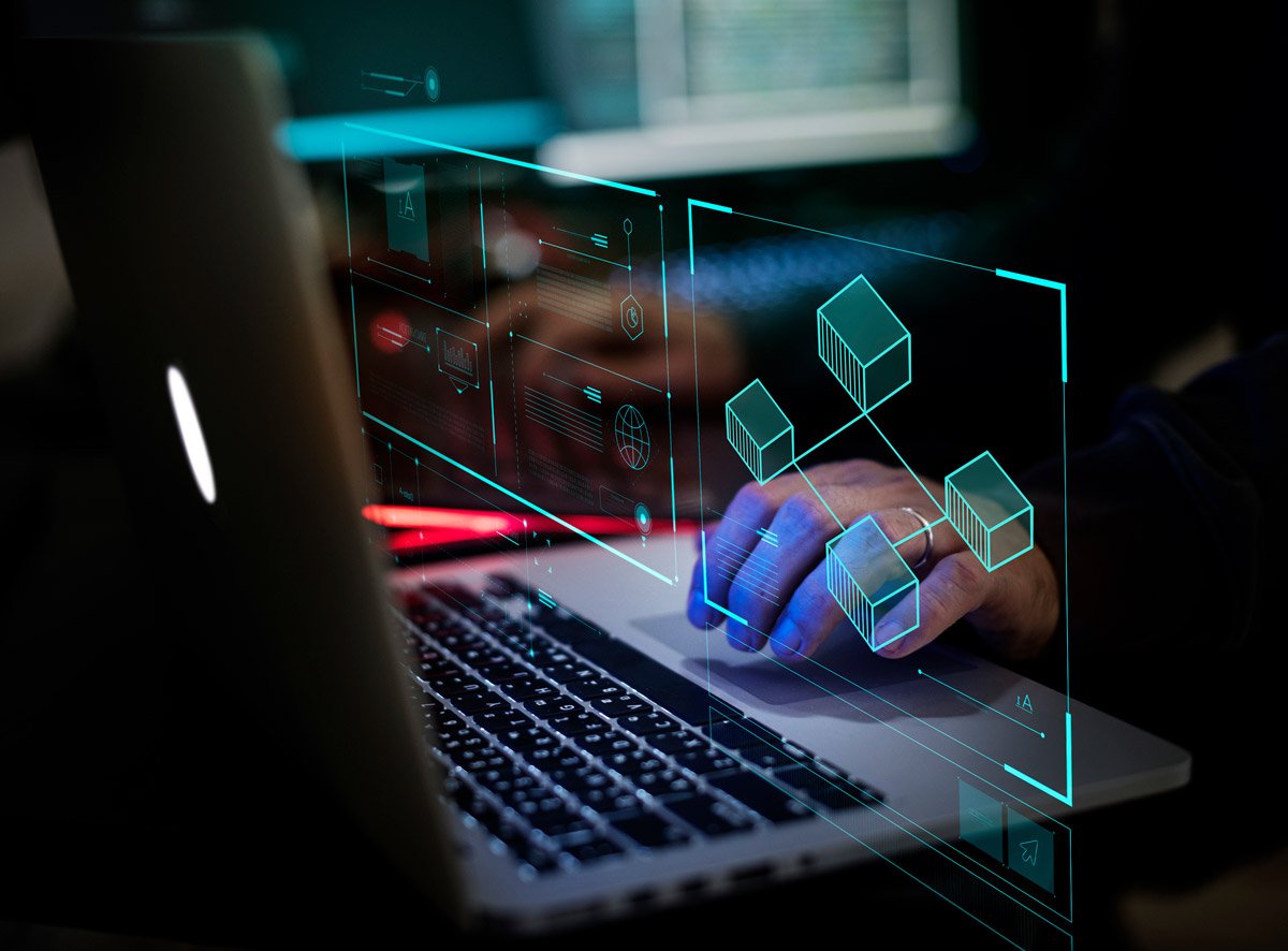 Hands on a laptop keyboard with a holographic overlay of linked cubes and data panels, representing connected devices being mapped