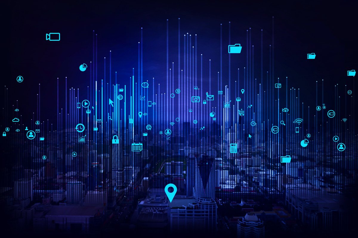 City skyline at night with device icons rising on light beams, representing connected devices spread across a smart city