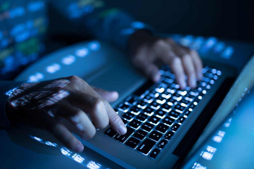 Tester's hands on a laptop keyboard in a darkened room during an internal network penetration test