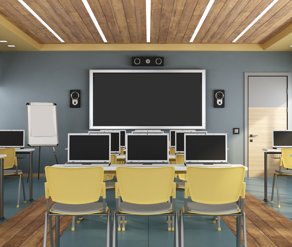 Classroom with rows of laptops on desks facing a wall mounted screen, the shared devices on a school network